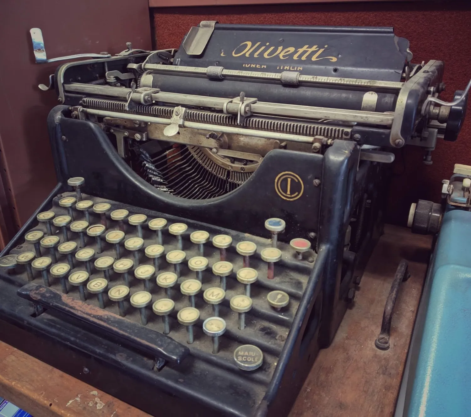 Macchina da scrivere Olivetti d'epoca con i tasti tondi, appoggiata su un tavolo di legno
