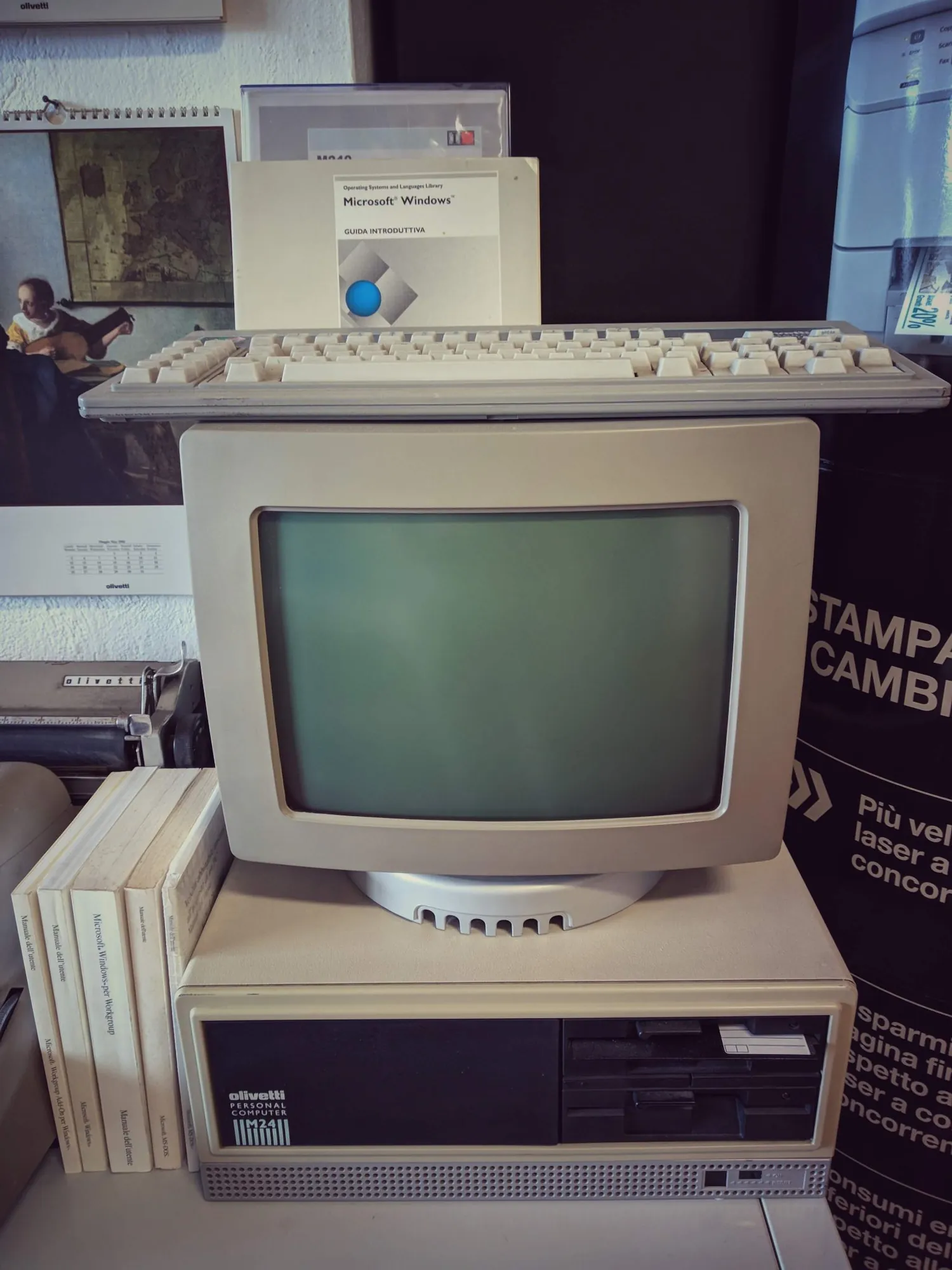 Personal computer Olivetti con monitor a tubo catodico, la tastiera e la guida di Microsoft Windows appoggiata sopra